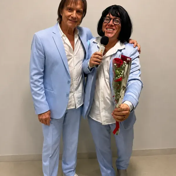 Chaveirinho caracterizado de terno azul claro com peruca, buquê de rosas e microfone